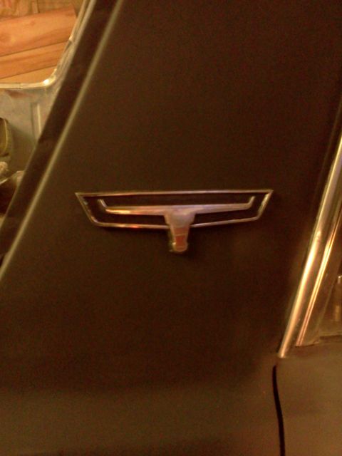 1967 Ford Ranchero - A car emblem is visible on a dark panel, with a chrome surround and red accents.