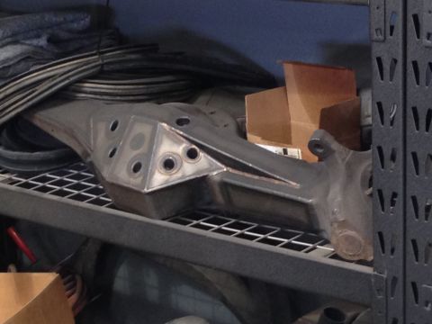 1986 Ford Bronco - A custom suspension part is stored on a metal shelf with other items.