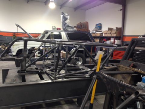 1986 Ford Bronco - Workshop scene with a Ford Bronco and a custom roll cage being worked on.