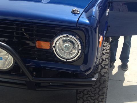 1986 Ford Bronco - Close-up of a blue Ford Bronco's front end, custom headlights and a black grille.