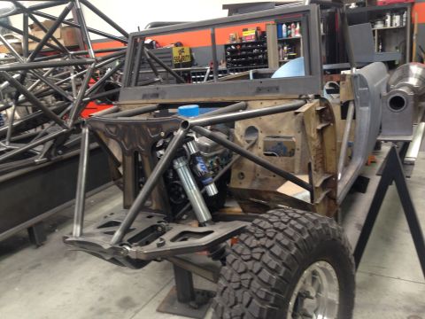 1986 Ford Bronco - This vehicle is undergoing modifications in a workshop, with extensive roll cage fabrication visible.