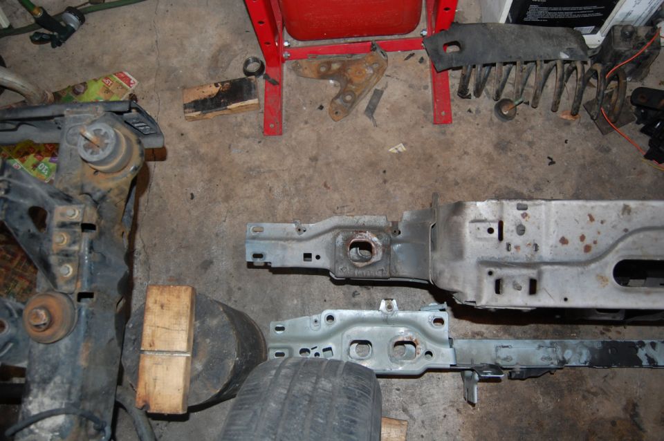 Car frame sections and suspension parts on a concrete floor