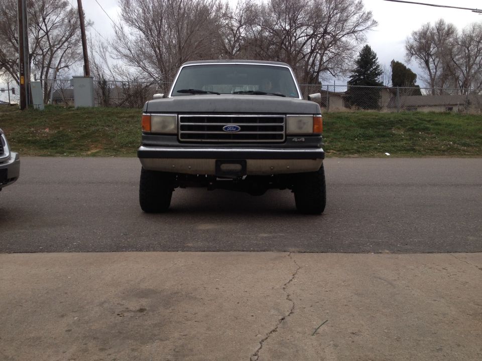Front view of a dark gray 1990 Ford Bronco with a chrome grille and 4x4 badging