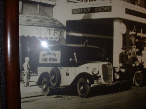 1999 Ford Crown Victoria - A vintage Washington State Patrol truck is parked outside a building with a sign for Reed & Bick Motors.