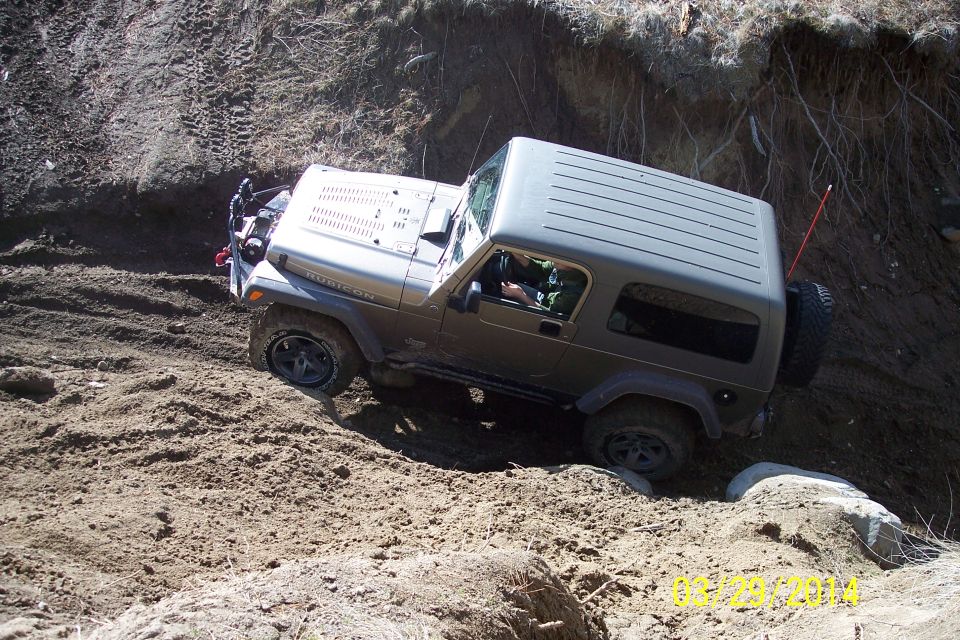 Silver 2005 Jeep Wrangler Rubicon navigating a steep dirt incline with tires digging in
