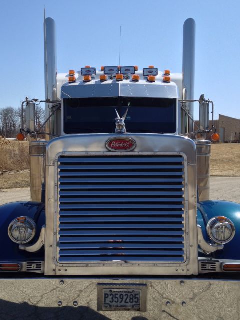 2003 Peterbilt 379 - Frontal view of a blue 2003 Peterbilt 379 truck with a prominent chrome grille and dual exhaust stacks.