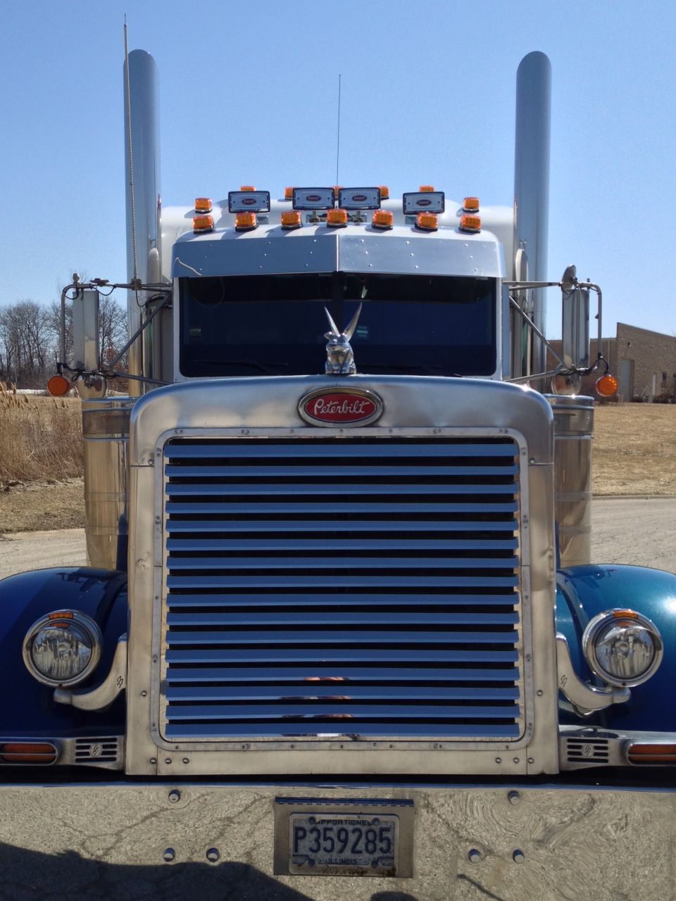 Blue Peterbilt 379 truck front view with chrome grille and exhaust stacks