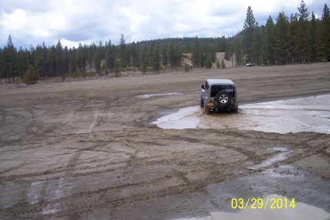 2005 Jeep Wrangler - A Jeep Wrangler navigates a muddy terrain with puddles, its off-road capabilities.
