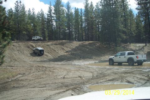 2005 Jeep Wrangler - Multiple vehicles navigate a challenging off-road course with muddy terrain and puddles.