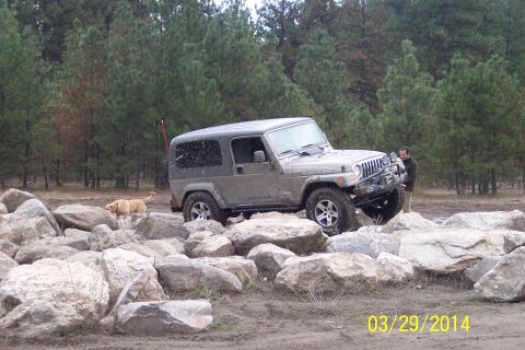 2005 Jeep Wrangler - A 2005 Jeep Wrangler navigates a rocky obstacle course with a dog watching.
