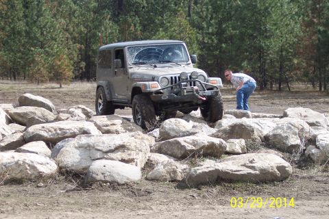 2005 Jeep Wrangler - A Jeep Wrangler navigates a rocky obstacle course, with a person observing the maneuver.