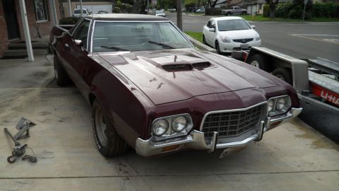 1972 Ford Ranchero - A maroon 1972 Ford Ranchero is parked on a concrete surface next to a trailer.