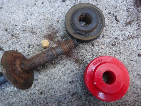 1993 Ford Taurus - Suspension parts including a rusty bolt and two bushings are laid out on a concrete surface.