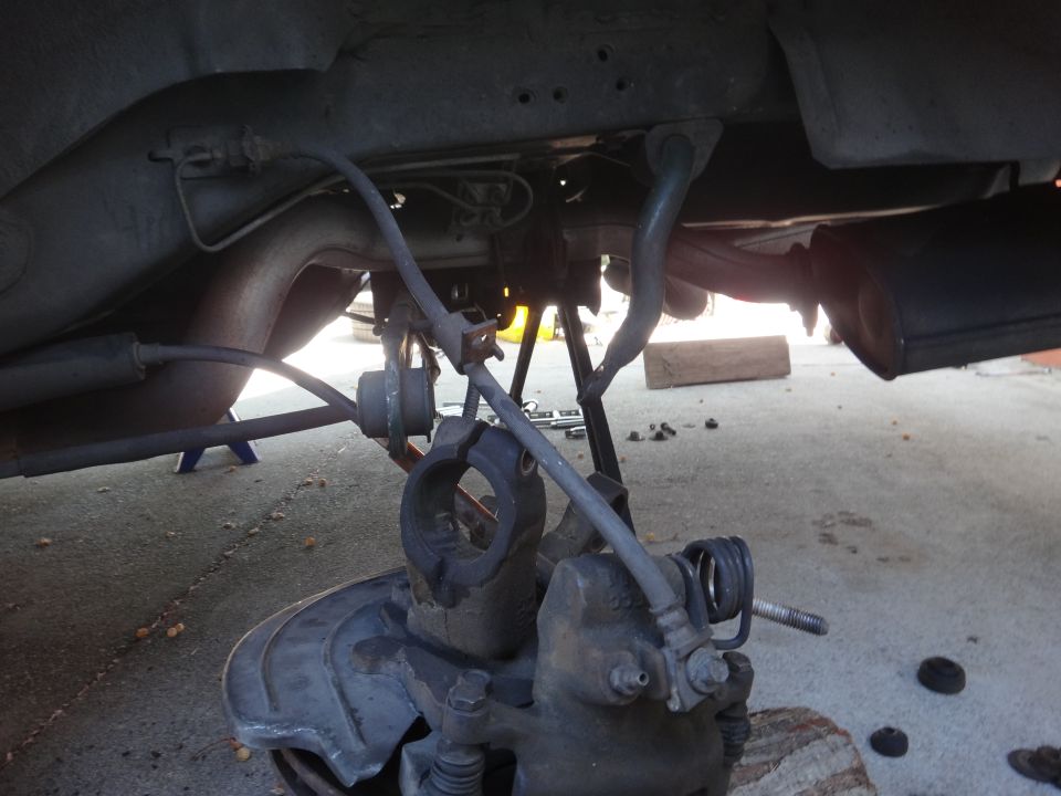 Close-up of a car's rear suspension with brake caliper, rotor, and exhaust visible