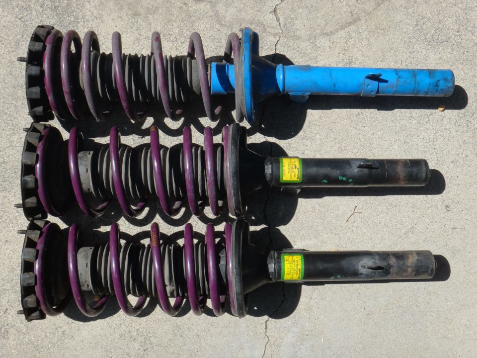 Three purple coilover struts with yellow labels and blue top mount
