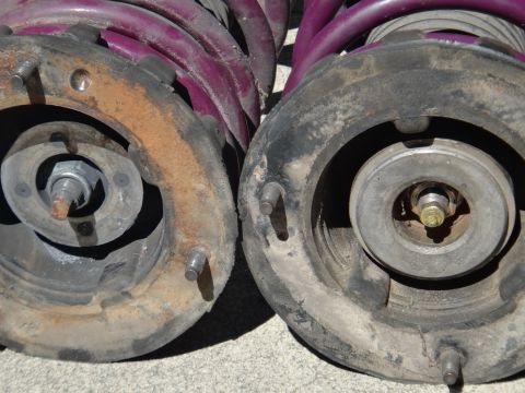 1993 Ford Taurus - Close-up of two used strut assemblies, one with a rusty mount and purple springs.