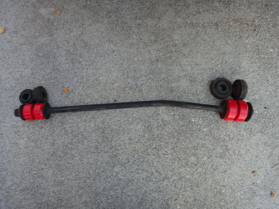 Sway bar with red polyurethane bushings and black rubber mounts on concrete