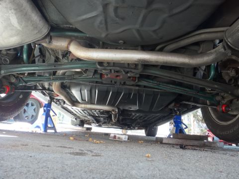 1993 Ford Taurus - The underside of a vehicle is visible, supported by jack stands, revealing the exhaust and suspension components.