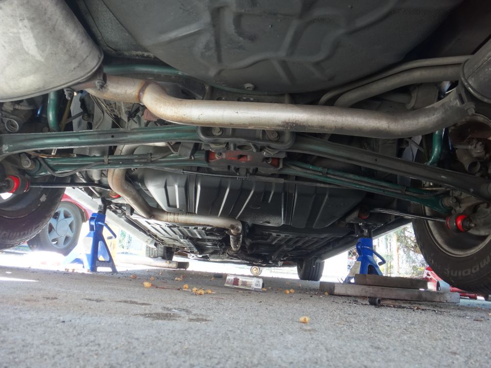 Underbody view of a car on jack stands, showing suspension and exhaust system