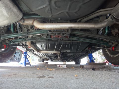 1993 Ford Taurus - Car's undercarriage, including exhaust system and suspension, is visible while elevated on jack stands.