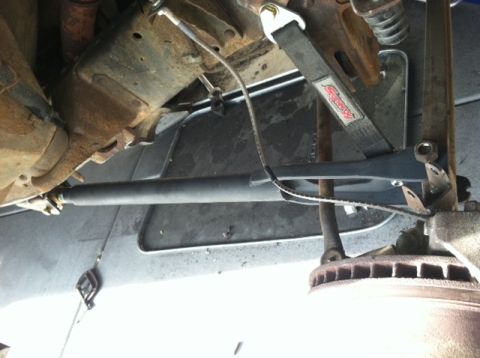 1977 Ford F-350 - Underside view of vehicle suspension parts, including a strap and brake rotor. The Supermotors.net logo is visible.