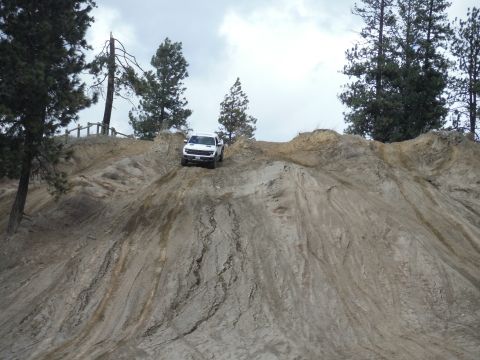 2005 Jeep Wrangler - A white pickup truck navigates a challenging off-road terrain on a cloudy day.