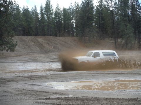 2005 Jeep Wrangler - White SUV navigating a muddy off-road course.