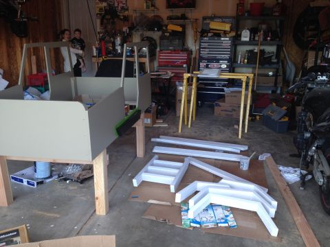 2005 Jeep Wrangler - A partially constructed wooden frame, resembling a vehicle, sits in a garage with various parts and tools scattered around.
