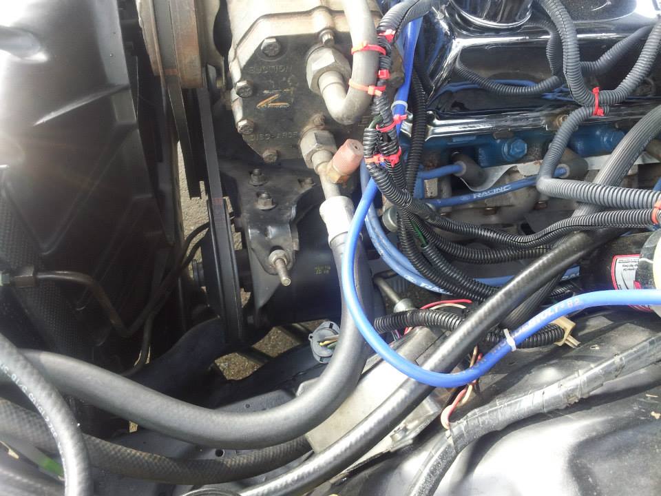 Engine bay detail showing the air conditioning compressor, belts, and hoses