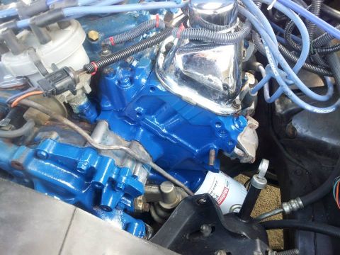 1976 Ford Ranchero - The engine bay features bright blue painted components and a chrome valve cover, with an oil filter in view.