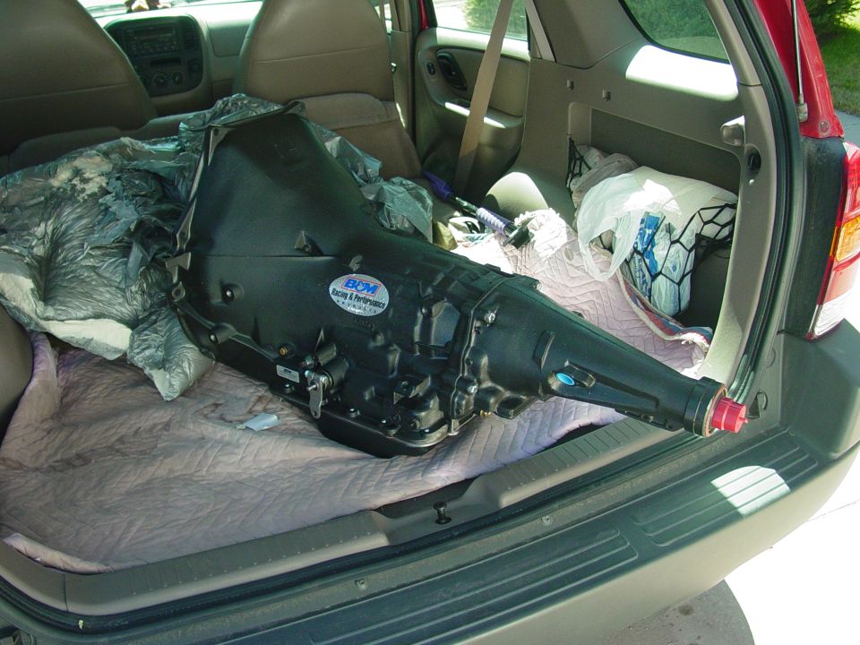 Black B&M automatic transmission lying on blankets in the cargo area of a red SUV