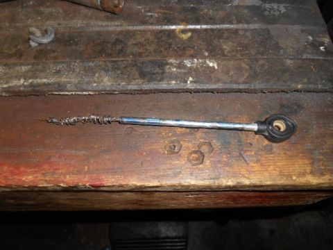 1994 Ford Bronco - A worn throttle cable end rests on a weathered wooden surface, showing signs of use and age.