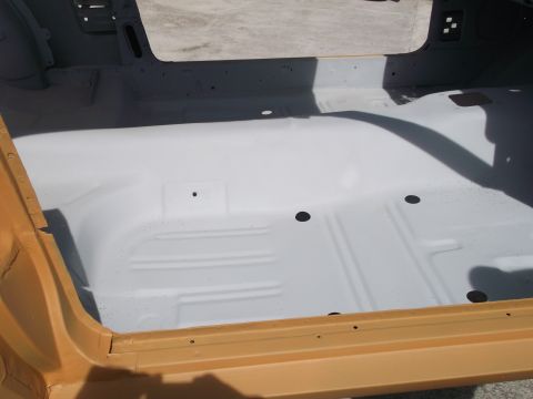 1967 Ford Mustang - The interior floor of a car, painted white, shows some structural details and a yellow door sill.