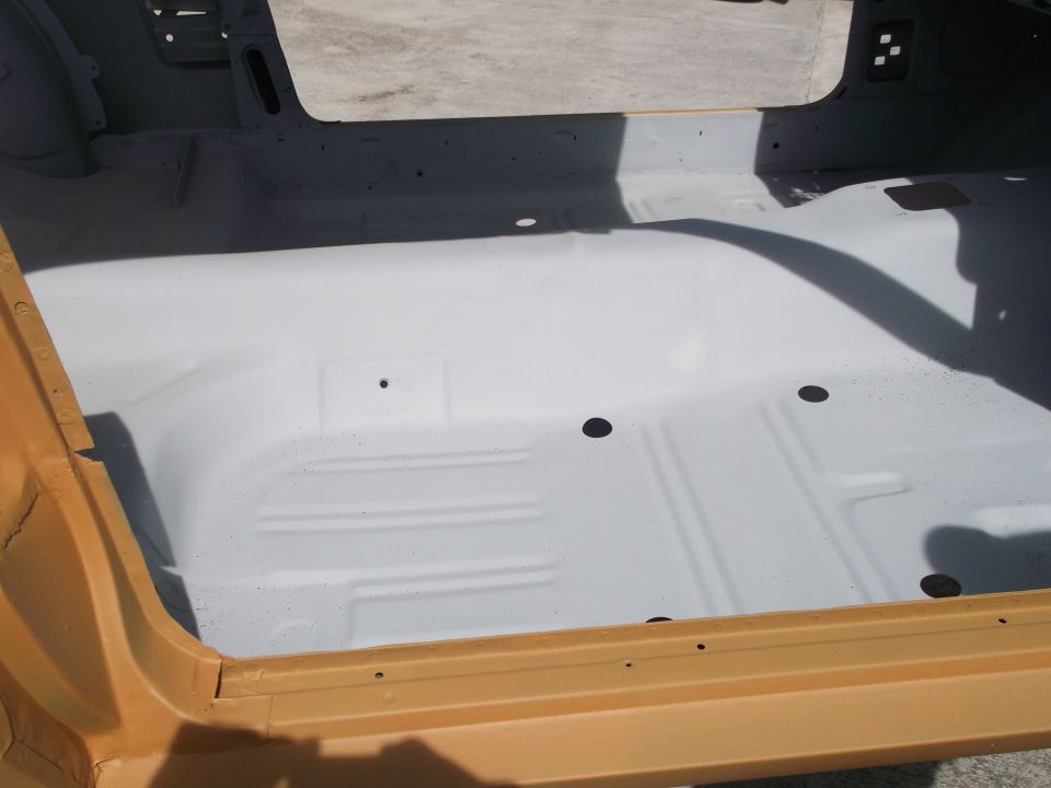 Car interior floor, painted white, with yellow door sill. Shadow visible