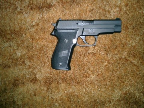 1994 Ford Crown Victoria - A black semi-automatic pistol is shown on a textured brown surface.