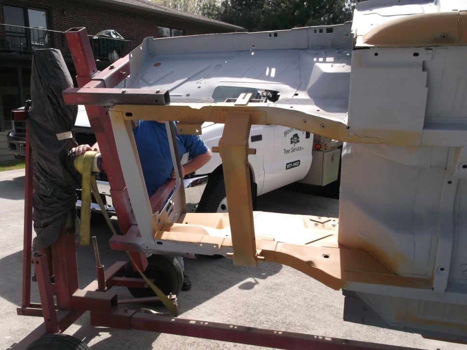 Car frame on a rotisserie with a white truck in the background