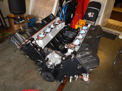 2003 Ford Crown Victoria - V8 engine on a stand inside a garage, showing the aluminum head, black valve cover and taped intake ports during assembly.