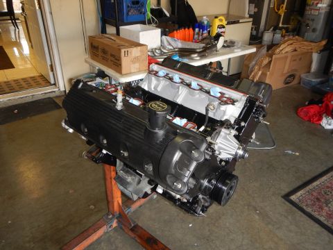 2003 Ford Crown Victoria - V8 engine mounted on an orange engine stand in a cluttered garage, with valve covers, intake manifold and taped ports during a rebuild.