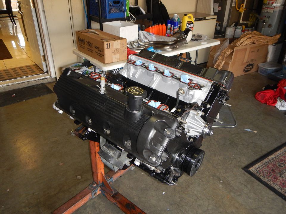 V8 engine on an orange stand in a cluttered garage workshop