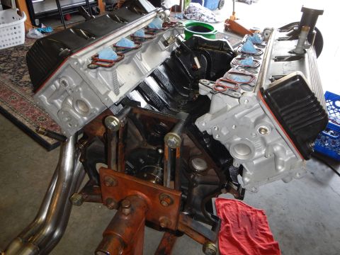 2003 Ford Crown Victoria - V8 engine on a stand in a garage with valve covers off and intake ports plugged with blue tape during assembly.