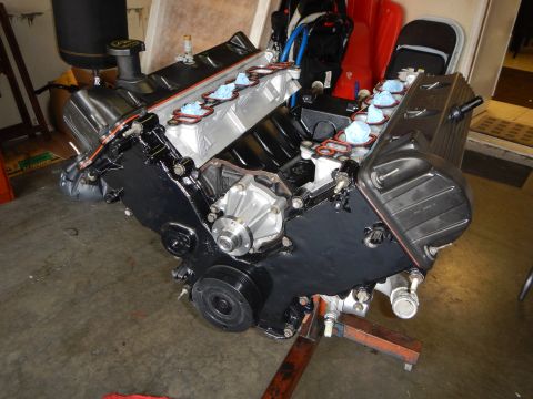 2003 Ford Crown Victoria - Rear angle of a V8 engine on a stand showing black valve covers, accessory housings, and bare cylinder block.