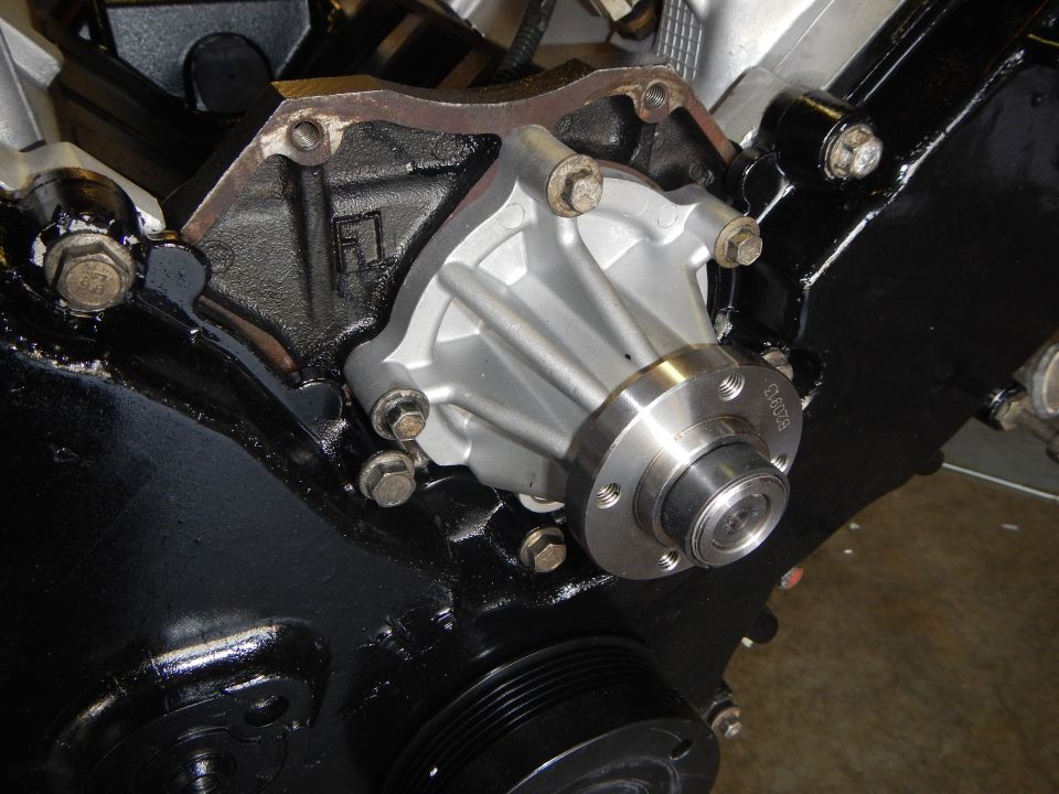 Newly installed aluminum water pump bolted to front of a V8 engine