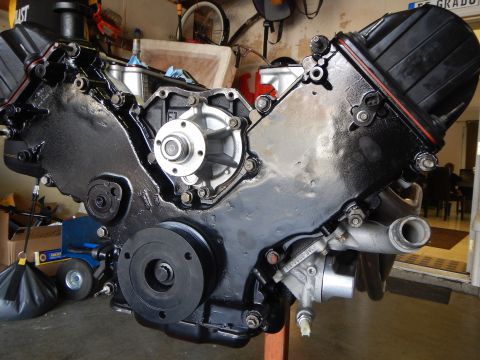 2003 Ford Crown Victoria - Front view of a black-painted V8 engine on a stand with installed water pump, crank pulley, and accessory brackets.