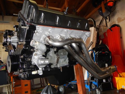 2003 Ford Crown Victoria - V8 engine on a stand in a garage fitted with shiny tubular stainless steel exhaust headers and black valve cover.