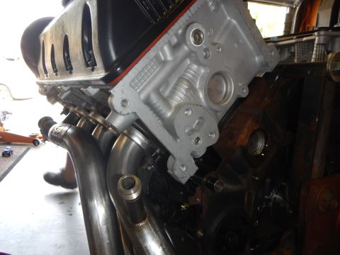 2003 Ford Crown Victoria - Close-up of a V8 engine's aluminum timing cover and front face with stainless header tubes routed along the side.