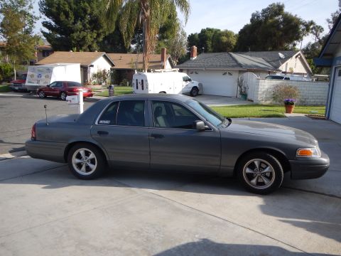 2003 Ford Crown Victoria - gray Ford Crown Victoria sedan shown in side profile parked on a residential driveway with houses behind.