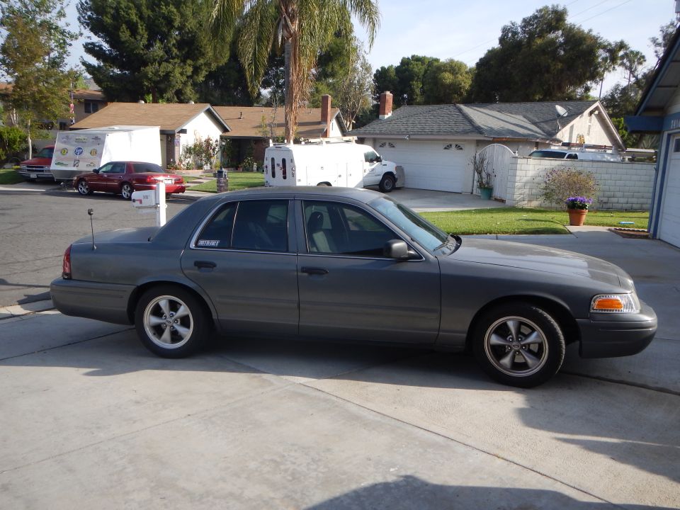 Gray Ford Crown Victoria sedan in profile parked on a driveway