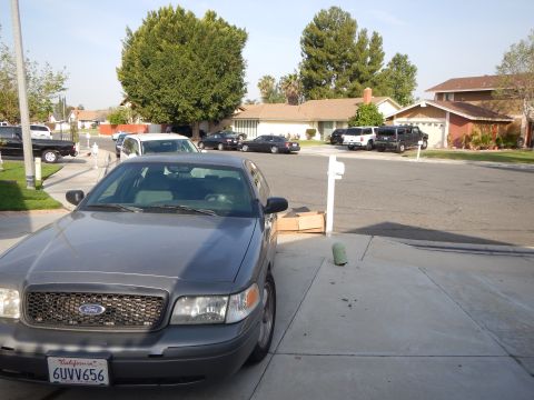 2003 Ford Crown Victoria - Front quarter of a gray Ford sedan with Ford grille badge and California plate 6UVV656 on a driveway.