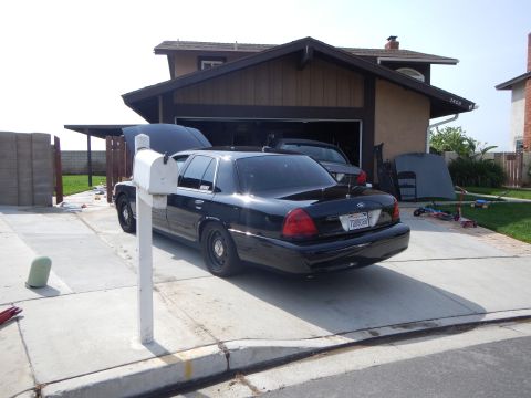 2003 Ford Crown Victoria - Rear three-quarter view of a black Ford Crown Victoria sedan parked in a residential driveway beside a white mailbox post.