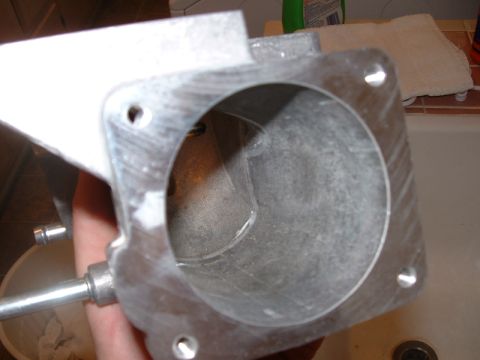 1998 Ford Crown Victoria - Metal throttle body part, likely for an engine, held up for inspection.